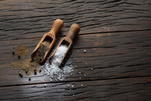 Sea salt and ground pepper in the wooden spoons on old wooden background. Two most popular ingredients that you put into food.