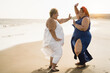 © DisobeyArt - Curvy women friends dancing on the beach having fun during summer travel vacation - Focus on faces