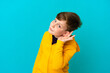 © luismolinero - Little redhead boy isolated on blue background listening to something by putting hand on the ear