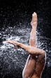Closeup athletic wet modern ballet dancer legs under splashes, streams, drops of rain water. Woman girl is dancing, doing acrobatic tricks. Contemporary art dance. Freedom and freshness concept.