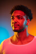 Portrait of a young african man at studio. Fashion male model in colorful bright neon lights.