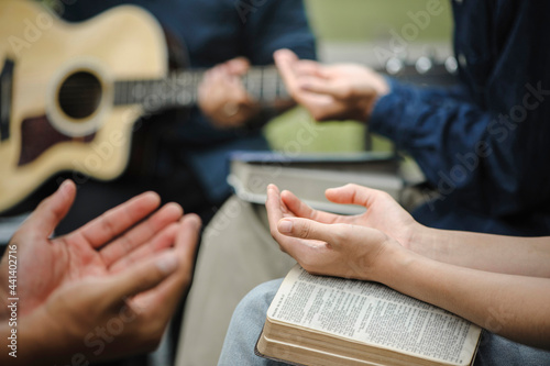 Christian family groups holding hands praying with Holy Bible. and play guitar to sing worship thanksgiving praise and seek the blessings of God with belief. reading Bible and sharing the gospel
