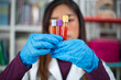 © Sam - Female asian doctor examining blood sample from the tube.