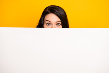 Wall Mural - Photo of funny cute young lady dressed white t-shirt hiding white bill board empty space isolated yellow color background