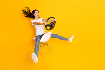 Poster - Full length profile side photo of excited happy girl sit chair automobile speed driver isolated on yellow color background