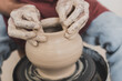 close up view of male african american hands shaping wet clay pot on wheel in pottery