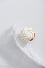 Wall Mural - top view of weightless and soft feather near tasty cupcake on white