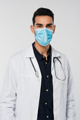 Poster - Arabian doctor in medical mask looking at camera isolated on grey