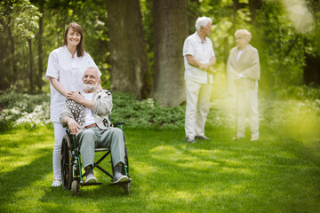 Canvas Print - Smiling caregiver with disabled man in the garden