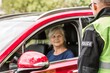 Policeman talks to an elderly lady sitting in a luxurious red car
