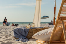 Beach Chair With Pillow, Candles, And A Whicker Crate Box And Umbrellas And The Horizon In The Background
