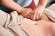 Close up of physician hands massaging woman abdomen during medical examination. Professional doctor examining patient stomach. Concept of healthcare, therapeutic massage and medical examination.