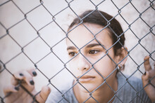 Portrait Of Young Girl Seen Through Chainlink Fence