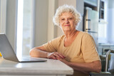 Fototapeta  - Confident elderly woman sitting at laptop computer at home