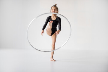 Little girl practising rhythmic gymnastic with a ring at white room. Children's gymnastics and training from an early age