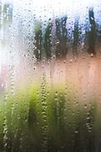 Water Droplets Of Humidity Condensation On Window Seen From Indoor With Backyard Bokeh In The Background