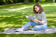 © spass - Beautiful young woman read book while relaxation in park at summertime