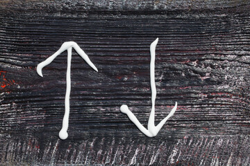 Two arrows painted with squeezed white paint from a tube, indicating two directions, up and down, background, texture.