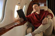 © New Africa - Young man using tablet in airplane during flight