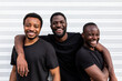 © ADDICTIVE STOCK - Cheerful black male friends embracing near striped wall