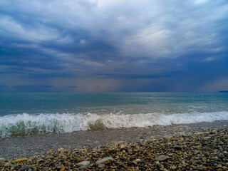 Wall Mural - Amazing sea sunset on the pebble beach, the sun, waves, clouds