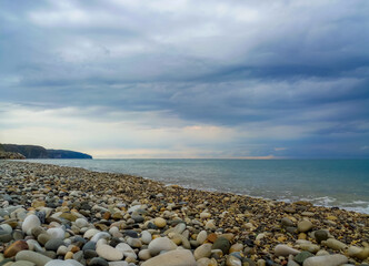 Wall Mural - Amazing sea sunset on the pebble beach, the sun, waves, clouds