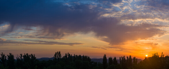 Wall Mural - Landscape with dramatic light - beautiful golden sunset with saturated sky and clouds.