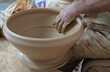 Potter working softly on pot with hand
