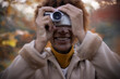 © Tom Merton/Caia Image - Happy young woman using digital camera in autumn park
