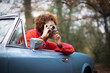 © Tom Merton/Caia Image - Young woman using digital camera in convertible