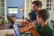 © Trevor Adeline/Caia Image - Father working from home at laptop with daughter on lap