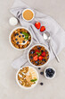 Served table, healthy breakfast. granola bowls with berry, banana and peanut paste and yogurt on grey background. Top view