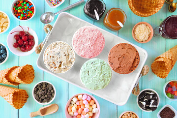 Poster - Summer ice cream buffet with different flavors and sweet toppings. Top view table scene on a blue wood background.