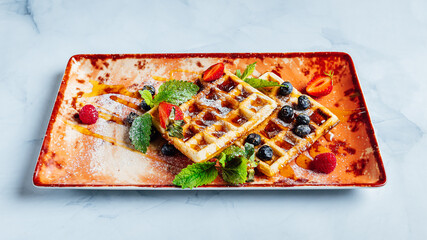 Sticker - Closeup of the sweet and delicious waffles covered in syrup and fruits on the plate