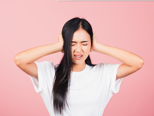 Wall Mural - Asian portrait beautiful cute young woman have closed ears with hand palms and close eyes, studio shot isolated on pink background, Thai female covers ears for loud noise with copy space