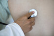 © liderina - Close up of doctor listening back of patient with stethoscope.