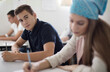 © liderina - Teenagers students sitting in the classroom working exam.