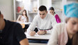 © liderina - Teenagers students sitting in the classroom working exam.