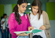 © liderina - Two students girls reading book together.
