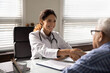 © fizkes - Smiling Caucasian female doctor in white medical uniform shake hand of old male patient in hospital. Happy woman GP handshake senior man close health insurance deal in clinic. Healthcare concept.