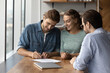 © fizkes - Happy young family couple clients signing insurance document, making good deal agreement with professional real estate agent, lawyer or broker at office meeting, celebrating purchasing own apartment.