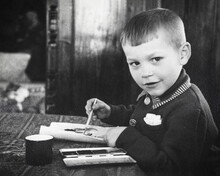 Retro Portrait Of Soviet Boy Drawing With Paints On Paper. Vintage Black And White Paper Photo. Early 1960s. Old Surface, Soft Focus. Transferred Property, Family Archive.