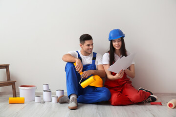 Wall Mural - Young couple with rollers, cans of paint and palette samples near light wall