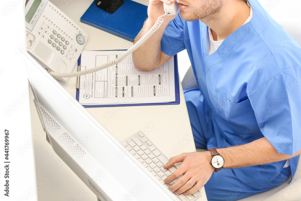 Male receptionist talking by telephone in clinic