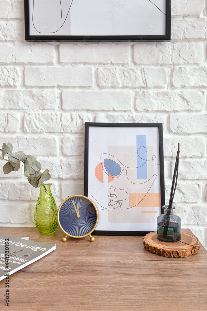 Table with decor and picture near brick wall