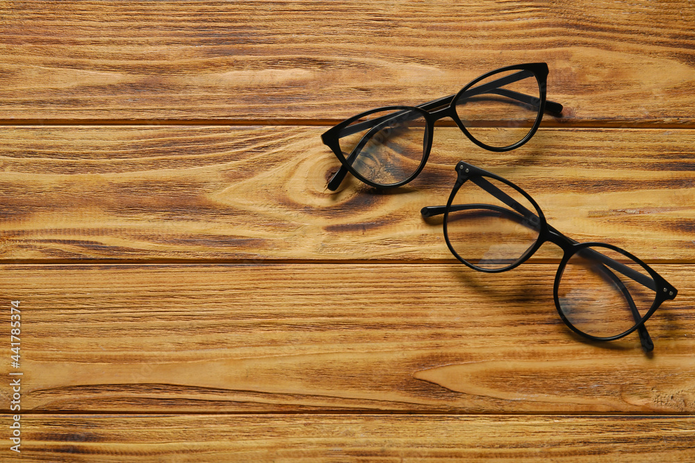Different stylish eyeglasses on wooden background