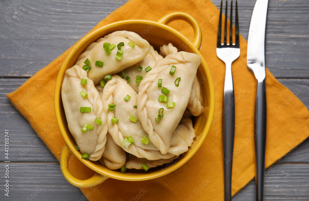 Pot with tasty dumplings on color wooden background
