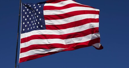 Wall Mural - 4k Slow Motion Real American Flag Waving In Wind Against a Deep Blue Sky