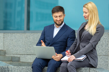 successful businessmen man and woman with documents and laptop in hands discuss business projects