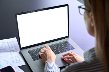Young female ceo executive manager using typing writing email letter using pc laptop computer with empty blank white screen for advertising at desk. Business technologies concept. Over shoulder view.